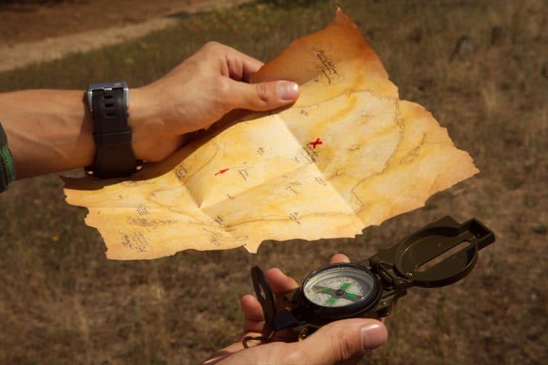 A person using a compass and treasure map.